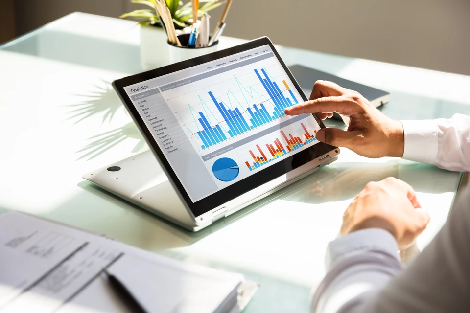 Homme d'affaires en costume travaillant à son bureau sur ordinateur avec interface logicielle affichant graphiques et données analytiques