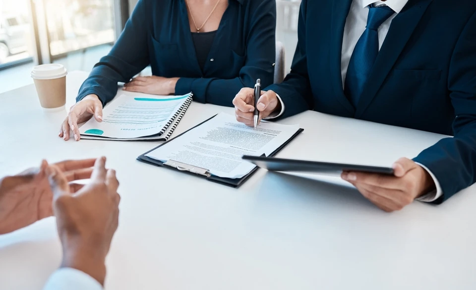 Divers collègues d'affaires discutant des documents utilisés pour accompagner la réunion mensuelle de l'entreprise, des gens d'affaires multidisciplinaires discutant du rapport de vente annuel de l'entreprise aux participants